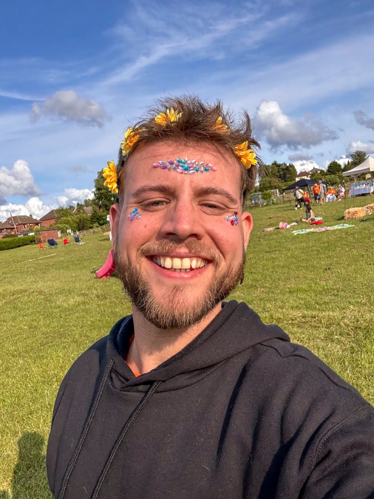 A smiling attendee with a flower crown and face gems